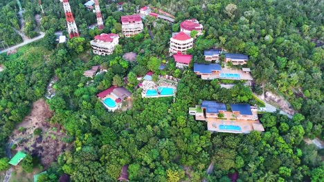 Luxury-hotel-on-tropical-jungle-hillside,-aerial-drone-view