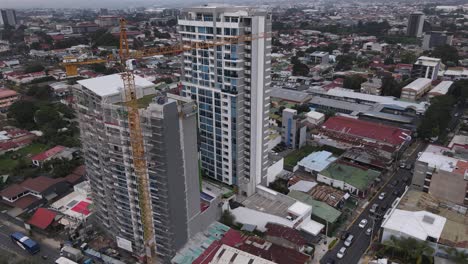 toma aérea cinematográfica de una grúa torre construyendo un rascacielos en costa rica.