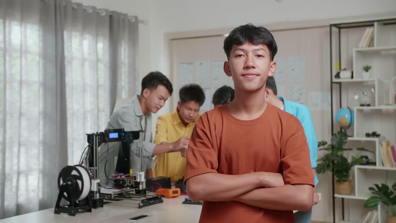 3d 프린팅과 노트북을 가지고 집에서 일하는 젊은 아시아 소년들의 그룹, 소년은 미소 짓고 카메라에 팔을 는 동안 그의 친구들은 사이보그 손에 대해 논의합니다.