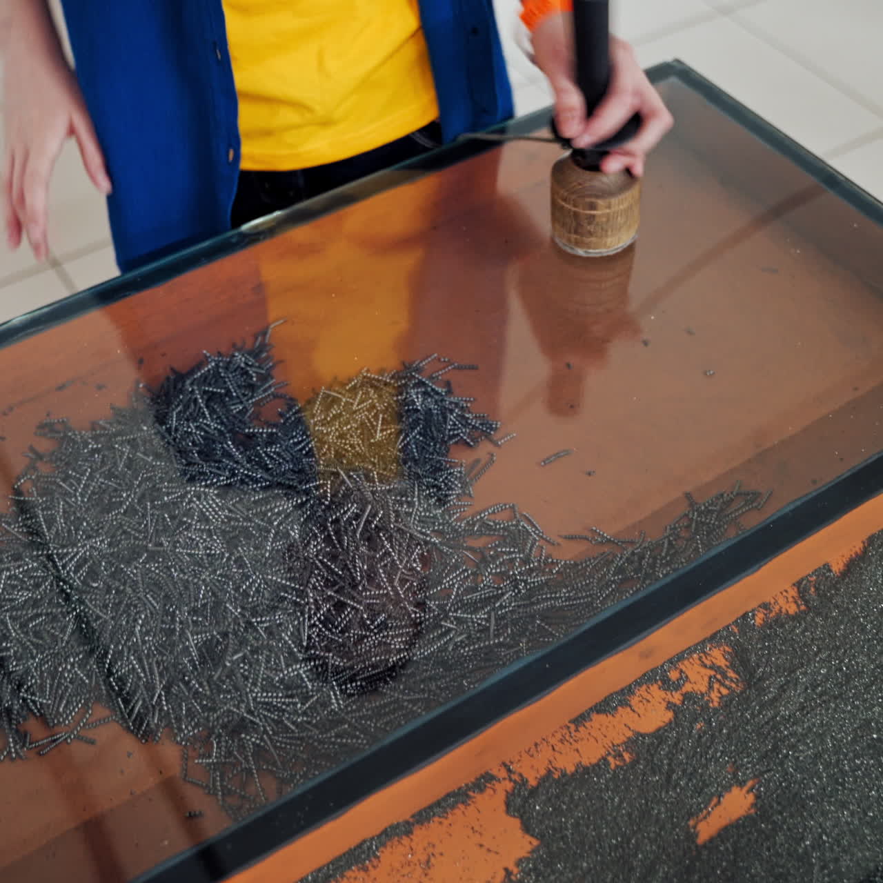Boy conducts research experience. Iron shavings and magnet. Science museum