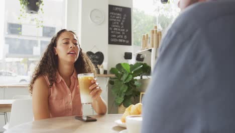 Happy-diverse-couple-spending-time-together-at-cafe,-drinking-coffee-and-talking