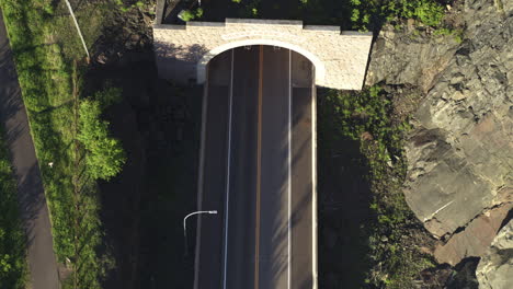 aerial top down, black luxury sports car driving out of tunnel
