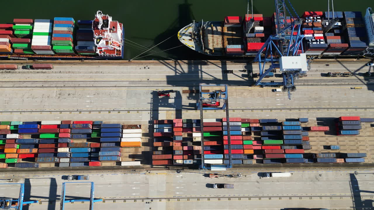 Birdseye drone shot above crates and ships at a large shipward, sunny day