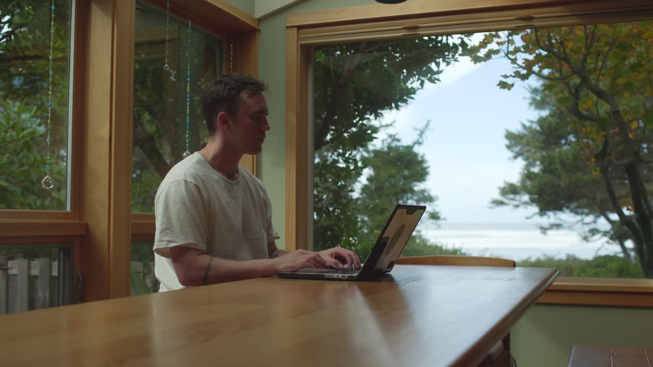 Man Working From Home Using Laptop - Wide Shot