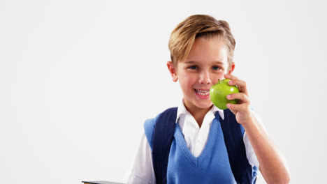 escolar sonriente sosteniendo libros y manzana