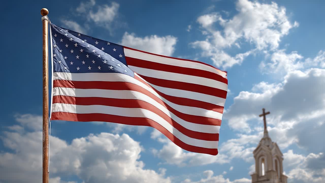 Bandiera americana che sventola contro un cielo azzurro brillante con nuvole leggere e un campanile di chiesa sullo sfondo, a simboleggiare libertà e speranza.