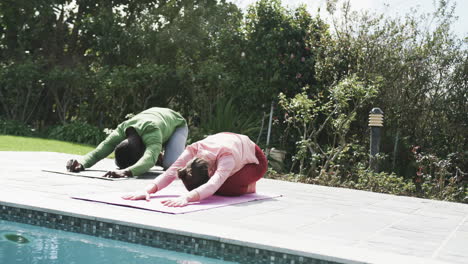 Feliz-Pareja-Diversa-Haciendo-Yoga-En-Un-Jardín-Soleado,-Cámara-Lenta