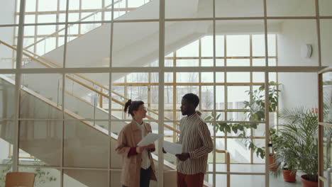 diverse coworkers discussing documents in modern office building