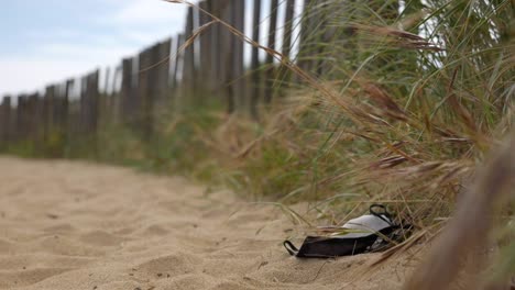 A-lost-or-discarded-face-mask-litters-the-coast-line---a-tragic-side-effect-of-the-current-pandemic