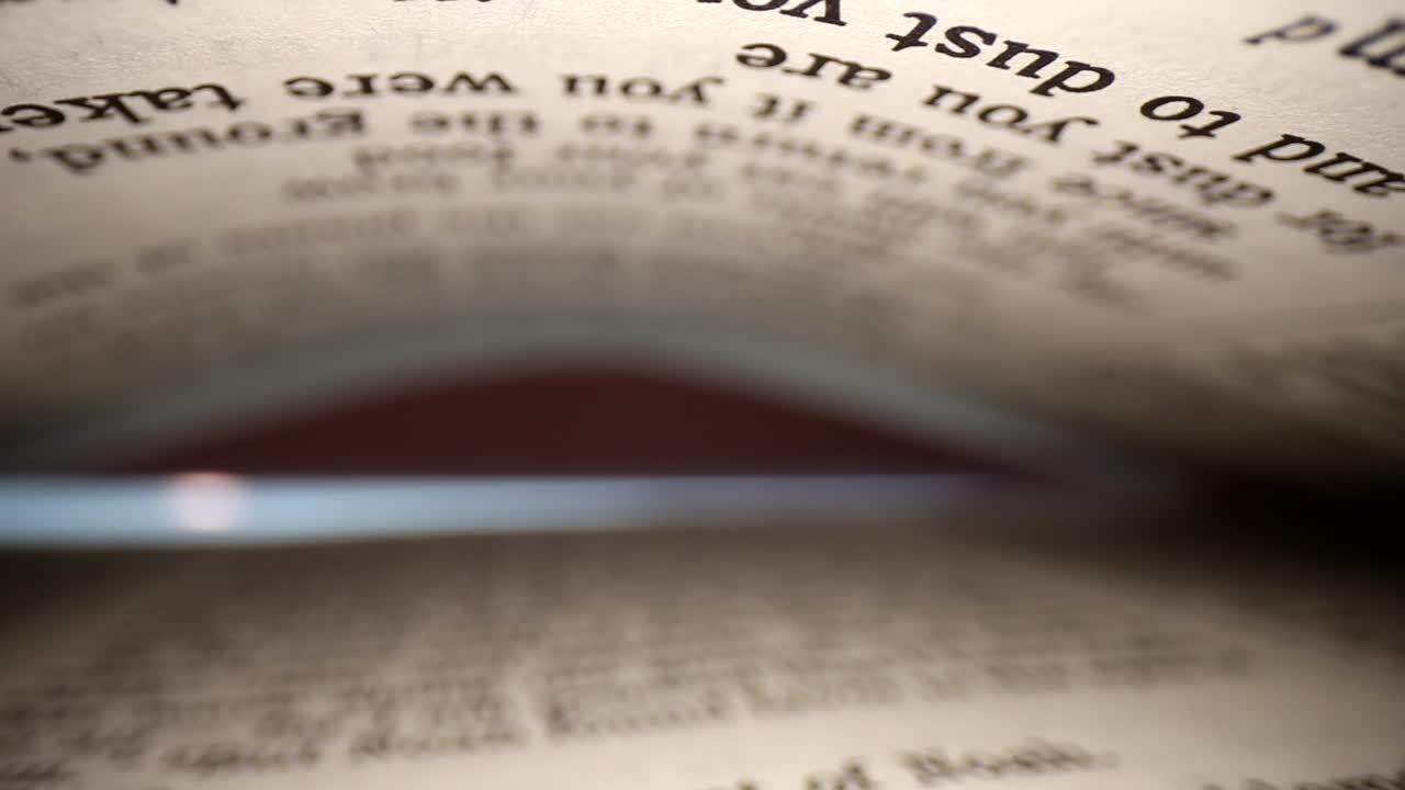 Slowly pulling lens out of a book @ words eye diagonal view of the pages