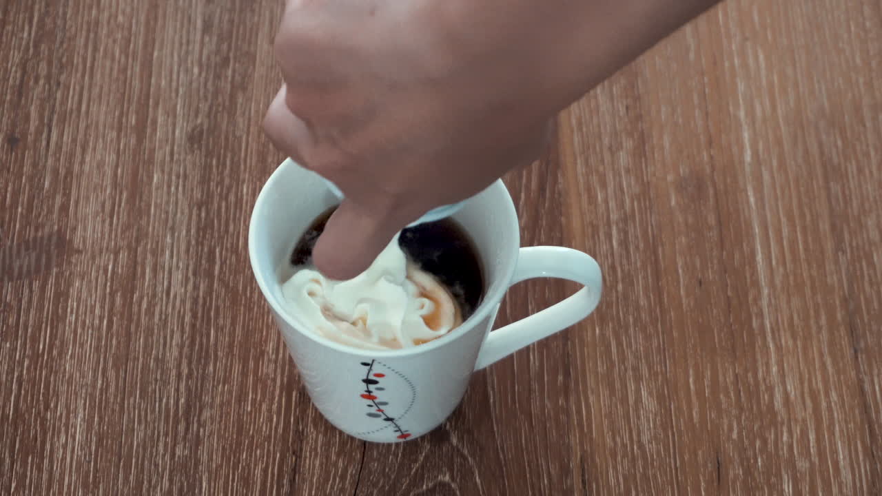 뜨거운 블랙 커피 위에 휘핑크림을 손으로 짜서