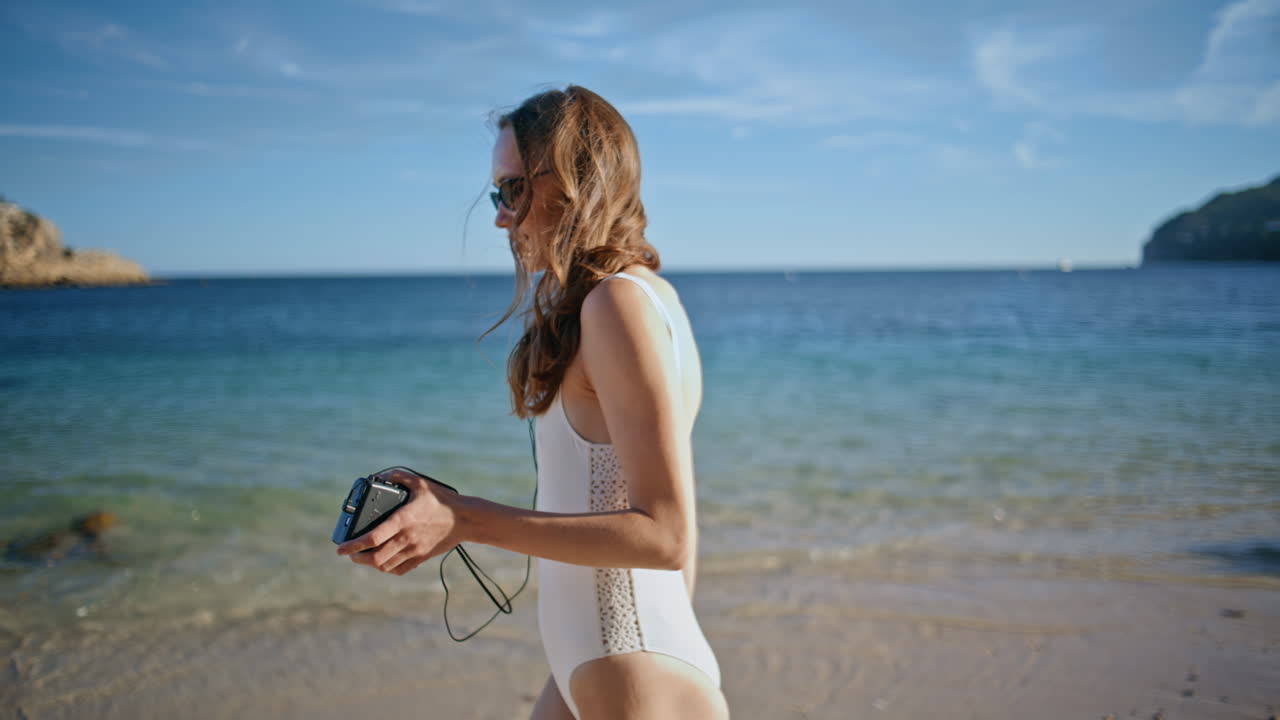 Carefree tourist walking beach listening music by retro cassette player closeup