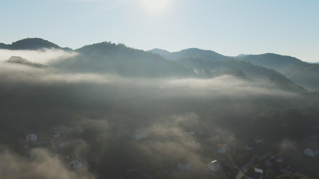 Foggy morning landscape with mountains and houses