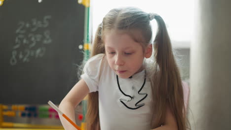 focused girl draws triangle sitting in room with blackboard
