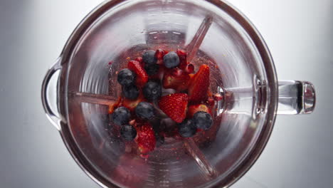 fresh ripe berries blending in mixer close up. top view preparing smoothie.