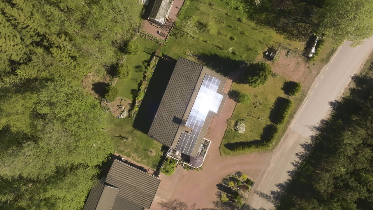 un drone de ojo de pájaro girando por encima de los paneles solares de espejo en el techo de una casa