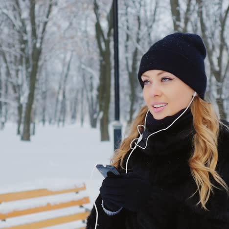 mujer camina y escucha música en el parque invernal 02