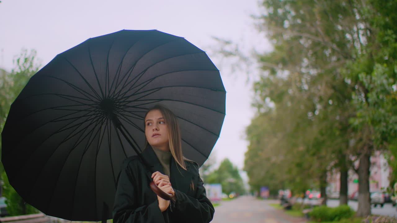 Gorgeous lady carry an umbrella over her head on city street during cloudy day with blurred background of trees buildings cars and lamppost showing urban lifestyle mood outdoor