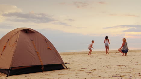 la madre juega con dos hijas soplando burbujas en primer plano se encuentra una carpa unas excelentes vacaciones en natu