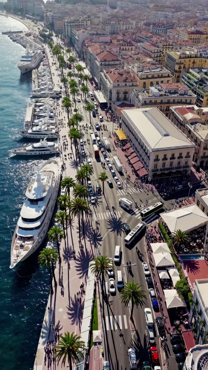 Aerial view of a vibrant coastal city with yachts and palm-lined streets, capturing the bustling