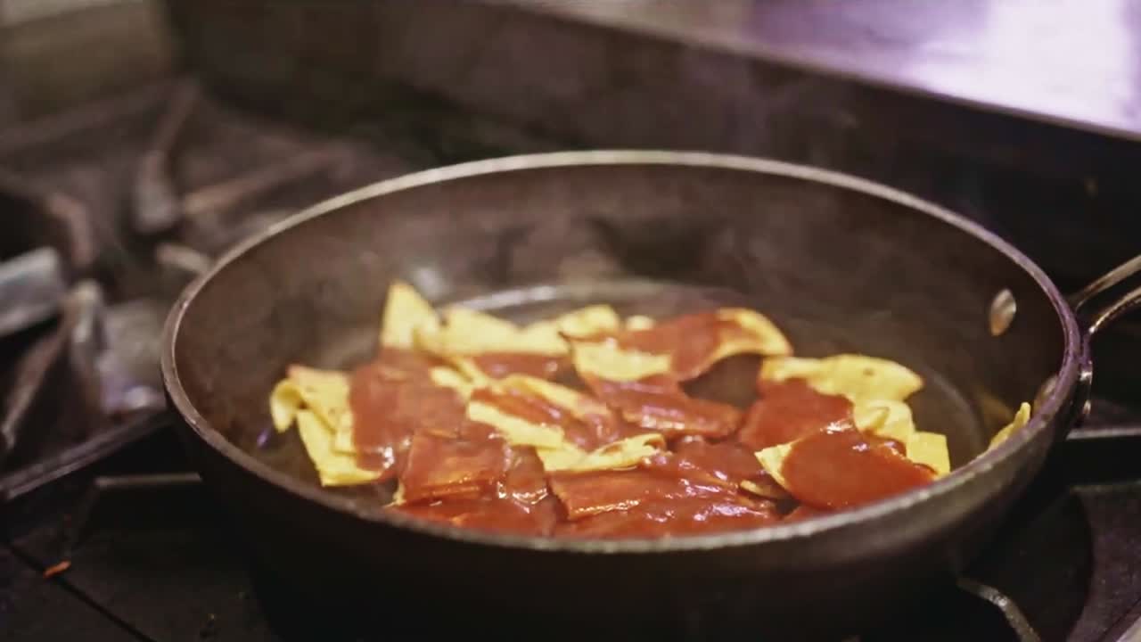 Pouring Red Sauce from a ladle on Frying Nachos in a health Vegan Mexican Kitchen