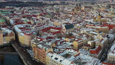 Prague-old-town-at-winter-with-light-snowfall,-drone-aerial-view,-historic-buildings-by-Vltava-river