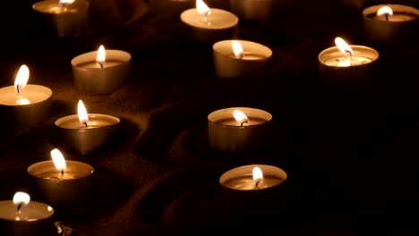 round candles burning in sand