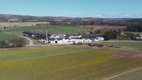 Aerial-view-of-Fettercairn-whisky-distillery-on-a-sunny-spring-day,-Aberdeenshire,-Scotland