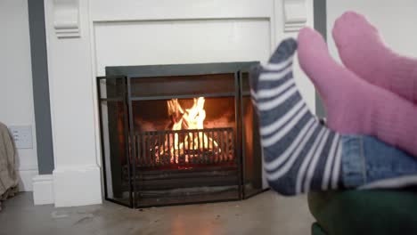 Feet-of-couple-in-socks-relaxing-at-home-in-front-of-open-fire,-slow-motion