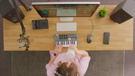 overhead view of female musician at workstation with keyboard and microphone in studio