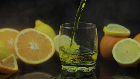 Pour-juice-into-glass,-orange-and-lemon-slices-on-background.-Slow-motion