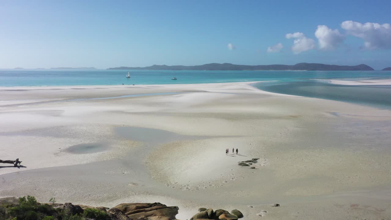 Four young people explore expansive beach on Whitehaven Beach, QLD