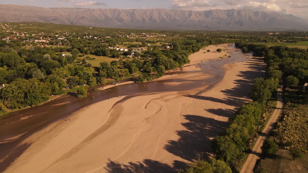 gente relajándose en el lecho arenoso del río con un hermoso paisaje de fondo, córdoba en argentina