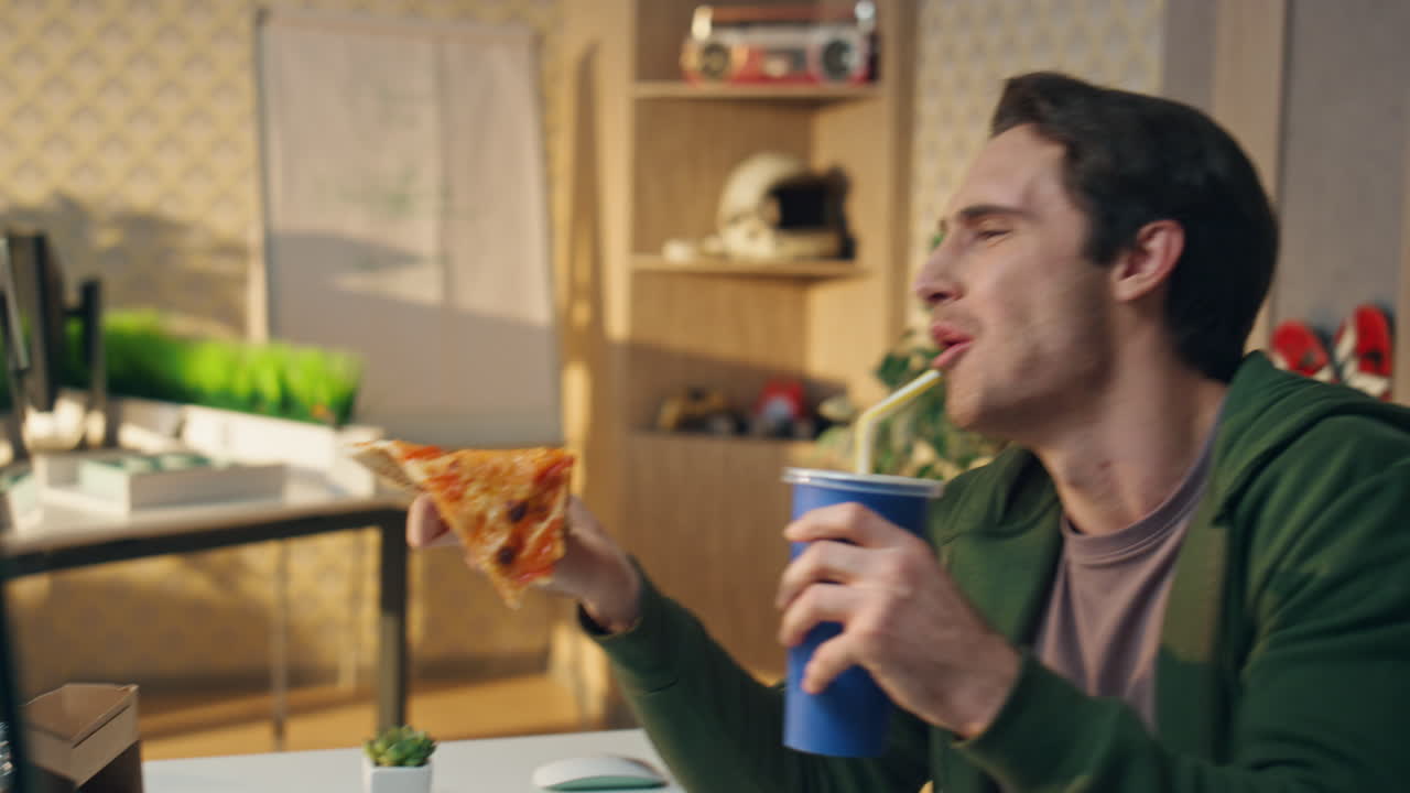 dos tipos comiendo pizza hablando en la mesa del monitor en primer plano. freelancers almuerzo