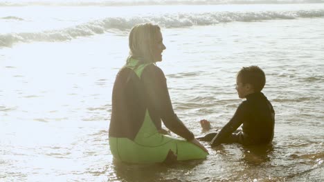 family sitting in water at sea coast