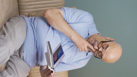 Vertical-video-of-Old-man-looking-at-family-album-with-trembling-hand.