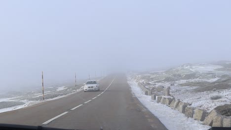 driving on a foggy road during snow winter in low visibility with car approaching from fog