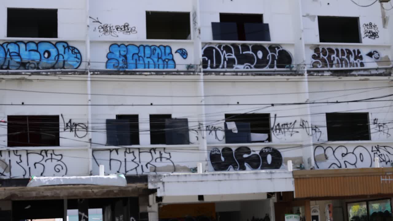 A series of graffiti artworks on a building facade in Phuket's Old Town, captured under natural daylight with a static camera