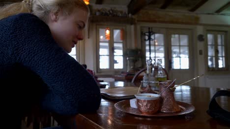 blonde woman in a blue sweater smiling at a turkish coffee service