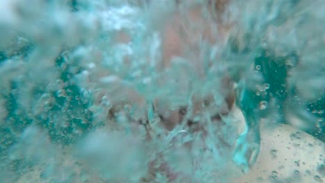 young man is jumping into a pool and diving under making bubbles by exhaling