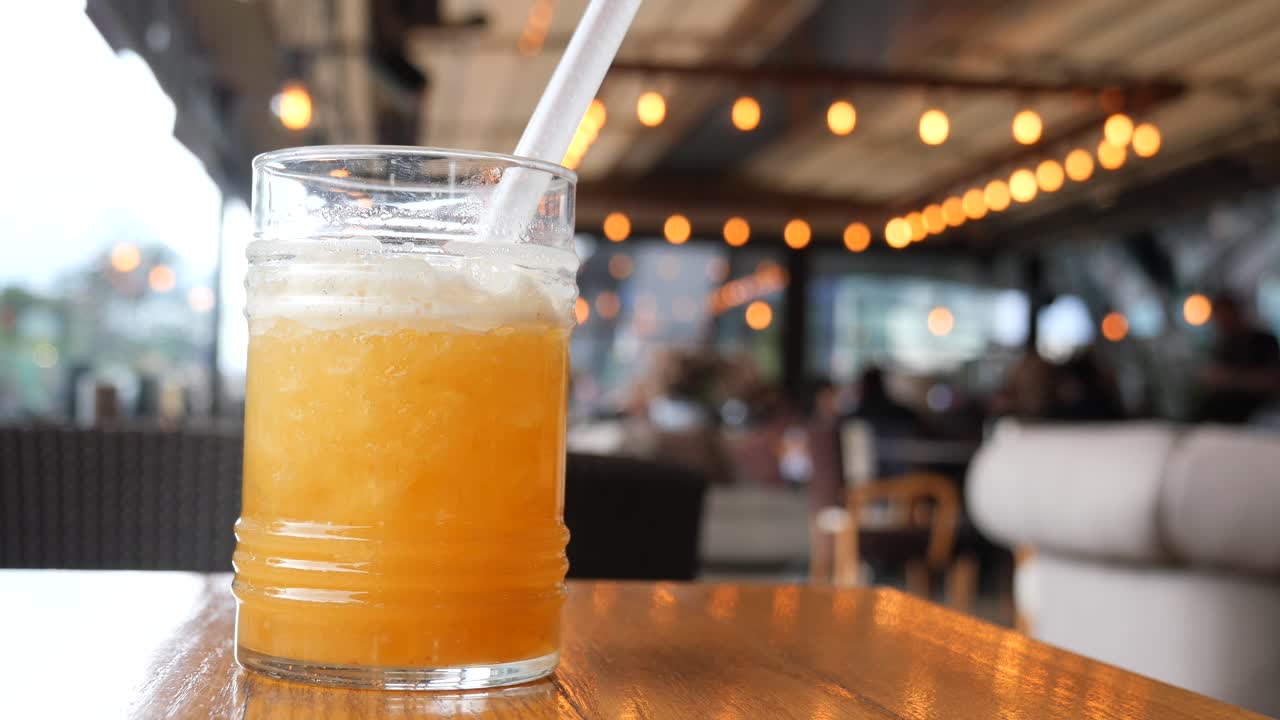 A glass of orange juice with a straw on a cafe table