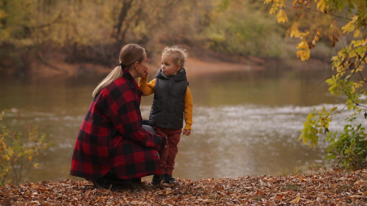 famiglia caucasica di giovane madre e figlio si stanno godendo la natura nella foresta nel giorno d'autunno paesaggio pittoresco con lago calmo