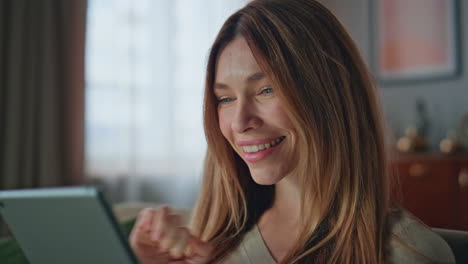satisfied woman checking email on tablet reading good news in home close up.