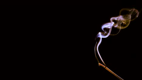 an incense stick burns and smokes.