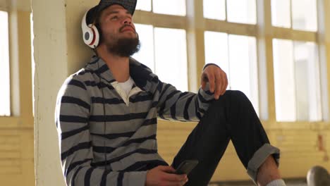 Young-man-listening-to-music-in-empty-warehouse