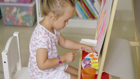 adorable little girl mixing colorful paints