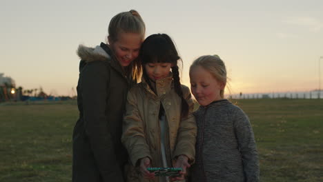 portrait of little girls posing taking selfie photo using smartphone camera technology enjoying park outdoors at sunset