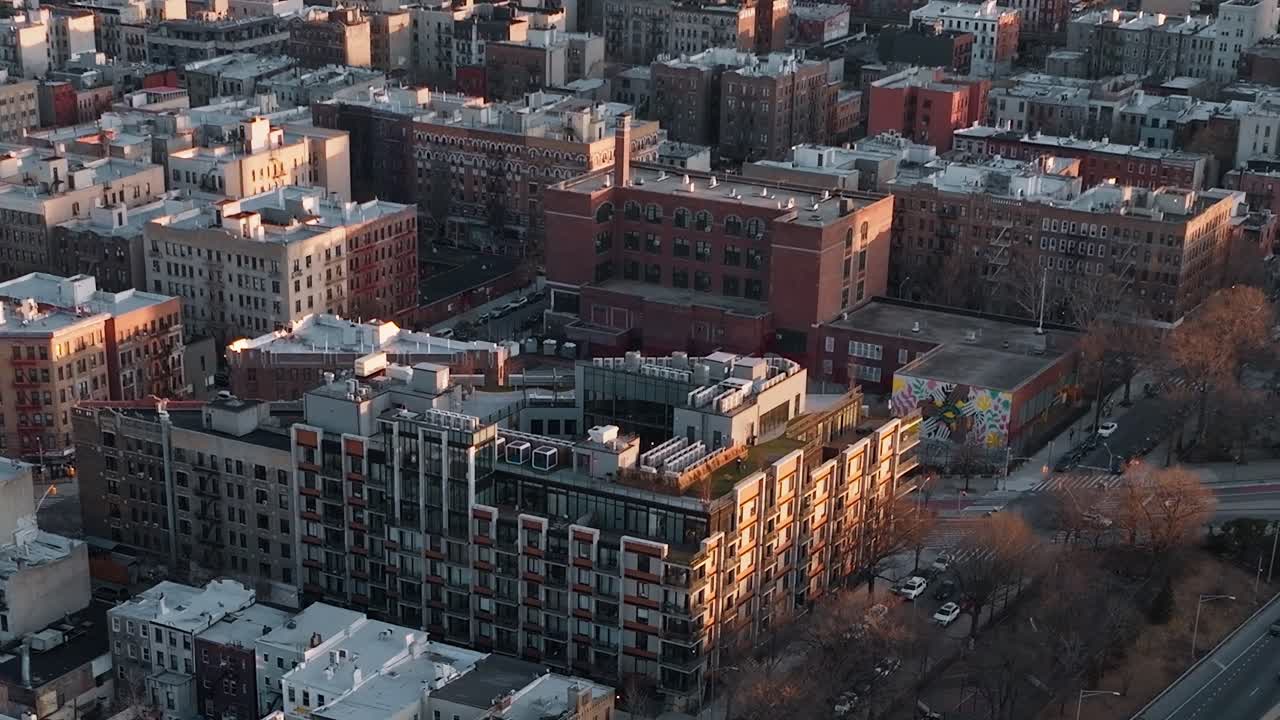 Pohled na newyorskou čtvrť při západu slunce s budovami a ulicemi