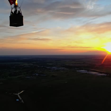people travel in hot air balloon. beautiful red aerostat in the form of a heart flying in the sky against orange sunset.