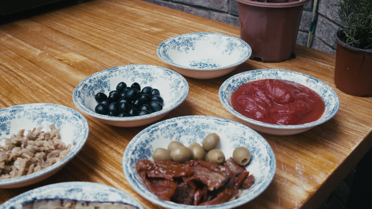desplácese por los ingredientes de la pizza dispuestos en platos sobre una mesa de madera